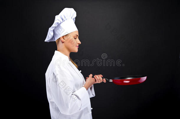 黑暗背景下年轻的女厨师用不同的工具