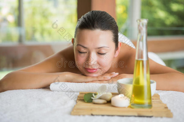 皮肤黝黑的女人躺在按摩台上，盘子里放着美容产品