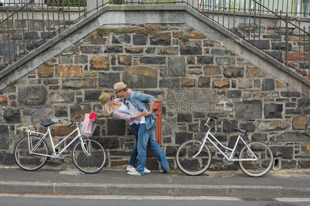 时髦的年轻夫妇骑着自行车在砖<strong>墙边</strong>跳舞