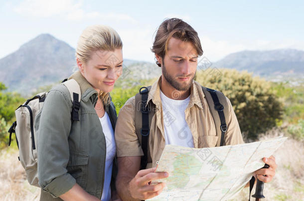 有吸引力的徒步旅行夫妇在山上看地图