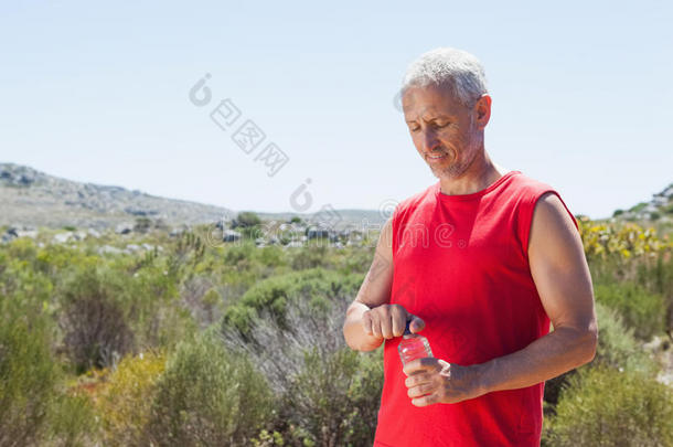 健康的男人在山路上打开他的水瓶