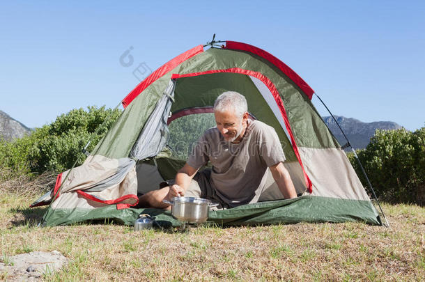 快乐的露营者在帐篷外的野营炉子上做饭