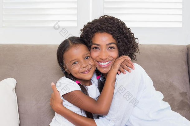 漂亮的妈妈坐在沙发上，女儿对着镜头微笑