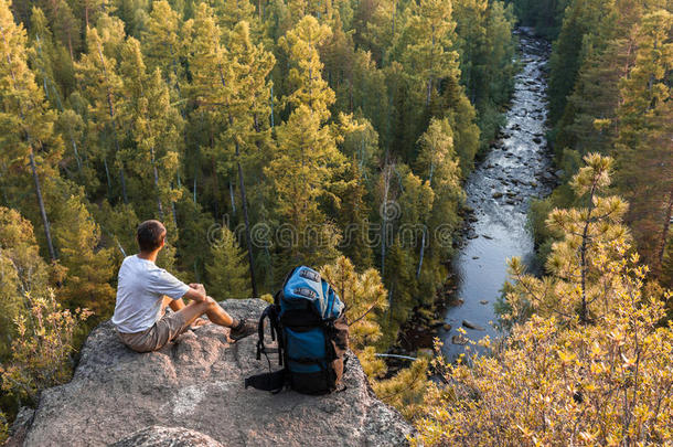 背包客坐在岩石上，看着美丽的景色