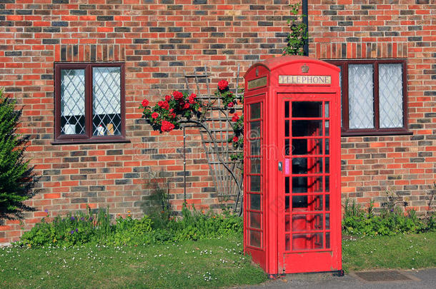 红砖墙前挂着浪漫玫瑰的怀旧电话亭