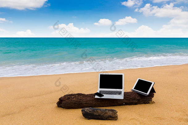 夏日海滩上的笔记本电脑、平板电脑和智能手机