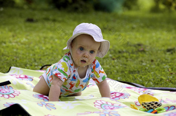 婴儿躺在草地上的野餐地毯上