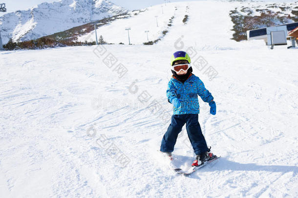 戴着滑雪面具的男孩在下山的雪地上学滑雪