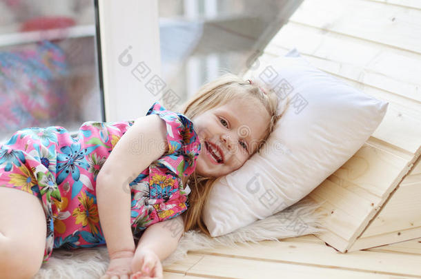 漂亮的金发女孩笑着躺在白色的枕头上
