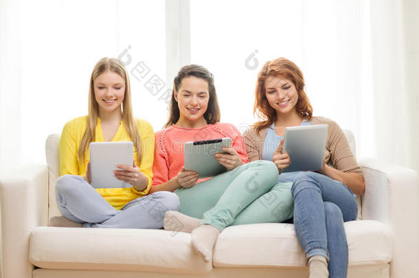 三个笑容满面的少女在家里拿着平板电脑