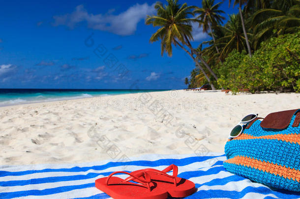 热带海滩上的包、毛巾和人字拖