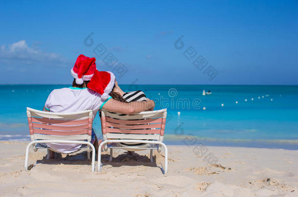 一对戴着圣诞帽的情侣在海滩上尽情享受