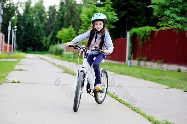 戴着蓝色头盔骑自行车的可爱小女孩