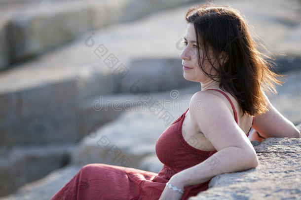 落日余晖中岩石海滩上的红衣女子1