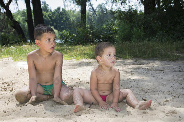 夏天在沙滩上坐着两个孩子在沙滩上看c