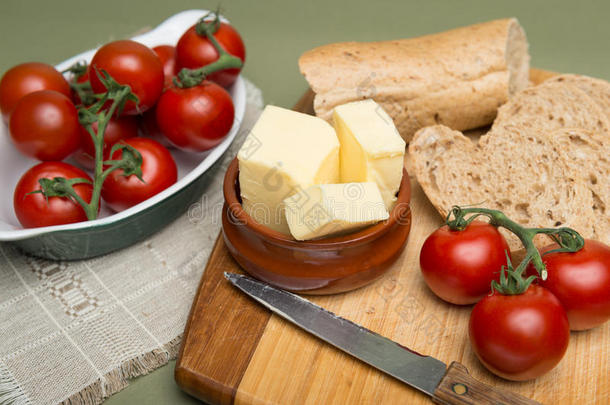 面包黄油/美味的有机自制面包和黄油，木板上有成熟的西红柿。