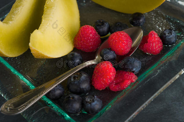 新鲜健康的水果放在黑色背景的玻璃甜点盘上。健康饮食理念