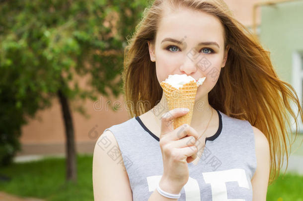 一个年轻美丽的快乐女孩，长发，在阳光明媚的日子里漫步在城市里吃冰淇淋