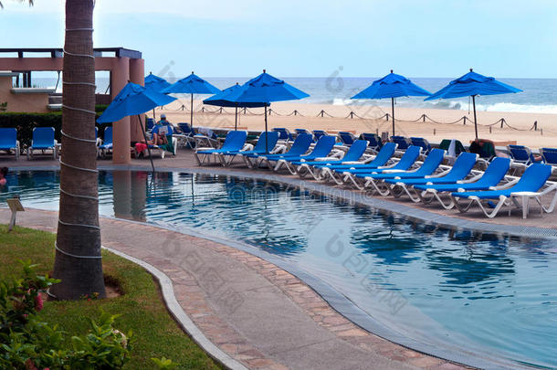 带躺椅的游泳池蓝色雨伞和海滩