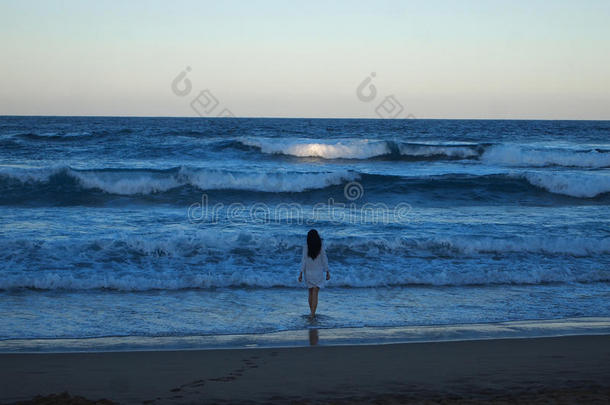 日落时进入大海的女孩。