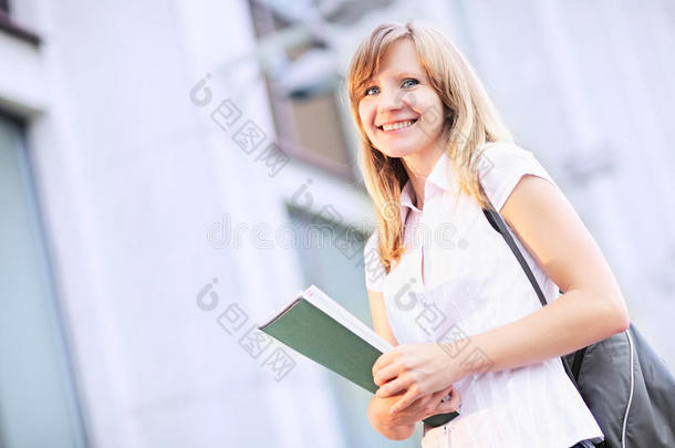 年轻的学生，美丽的白种女人，早上站在模糊的<strong>大学建筑</strong>背景上。