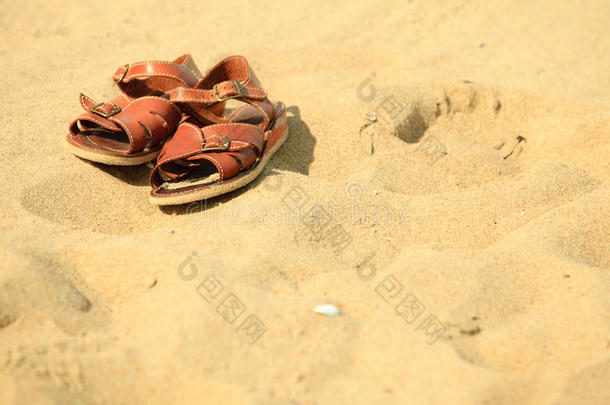 鞋。沙滩上的棕色皮凉鞋。夏天。