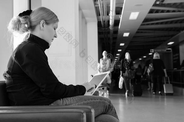 一位年轻女子在机场休息室使用她的数字平板电脑
