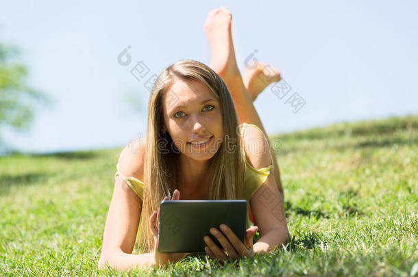 躺在草地上放松的女孩喜欢阅读电子书