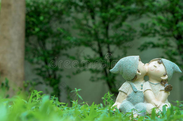 一个女孩和一个男孩在花园里接吻坐着玩偶