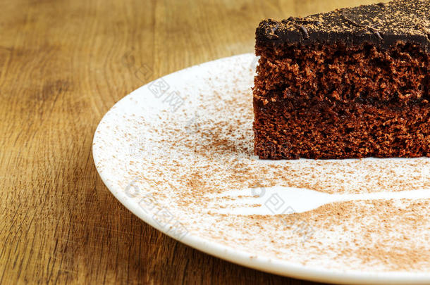 一块巧克力蛋糕，放在一个白色盘子里，上面放着可可粉