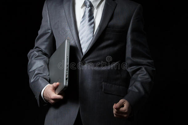 身着灰色西装的商人一只手拿着笔记本电脑