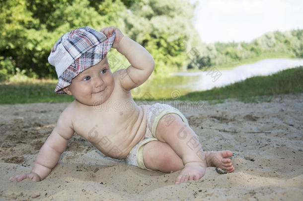 夏天在河边的海滩上坐着一个有趣的小男孩