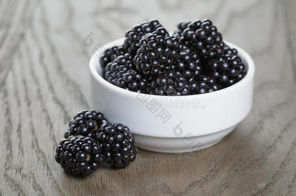 成熟的黑莓放在旧橡木桌上的白碗里