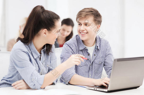 两个微笑的学生拿着笔记本电脑