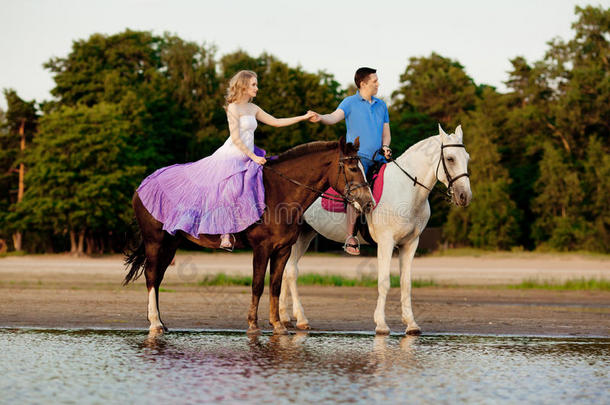 两个<strong>骑</strong>马的人在海滩上日落时<strong>骑</strong>马。情侣<strong>骑</strong>马。一个年轻的男人和一个漂亮的女人在海上。只读存储器