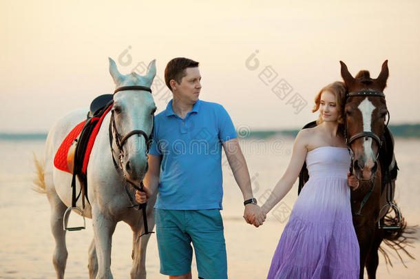 两个<strong>骑</strong>马的人在海滩上日落时<strong>骑</strong>马。情侣<strong>骑</strong>马。一个年轻的男人和一个漂亮的女人在海上。只读存储器