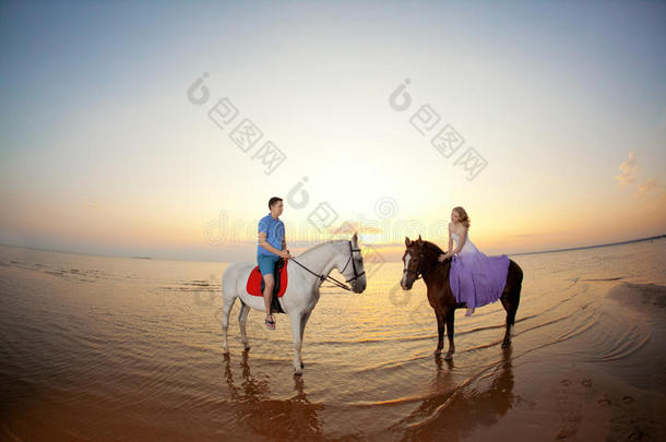 两个<strong>骑马</strong>的人在海滩上日落时<strong>骑马</strong>。情侣<strong>骑马</strong>。年轻漂亮的男人和女人在海上<strong>骑马</strong>。