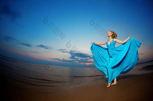 海滩上穿着蓝色晚礼服的豪华女士。美女