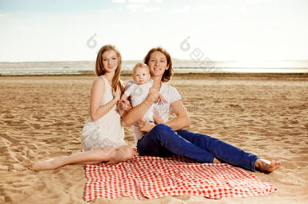 一家人在海滩野餐。妈妈，爸爸和孩子在附近