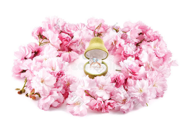 金戒指与蓝色黄玉在礼品盒中，珠宝形状为梨形，周围有粉色樱桃花。