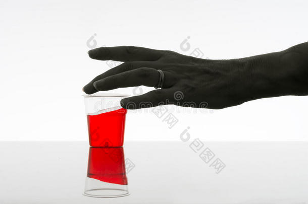 女人伸手去拿红色饮料。酒精，成瘾概念。黑暗。