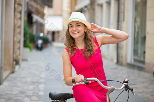一个戴着帽子和粉色裙子骑自行车的女孩