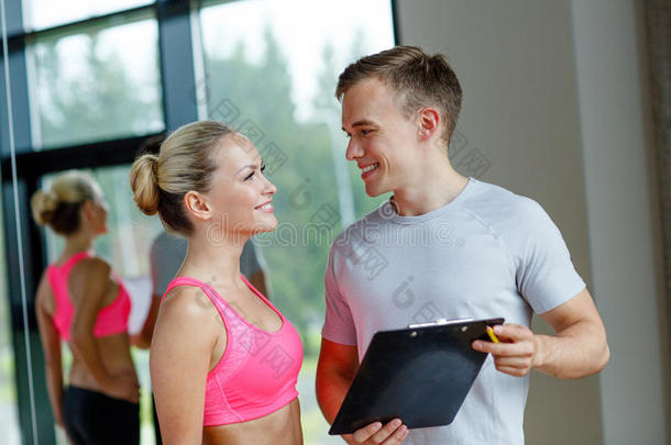微笑的年轻女子和私人教练在健身房