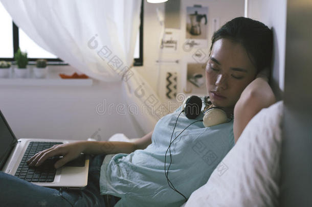 随意的年轻女人在家里用笔记本电脑睡觉。