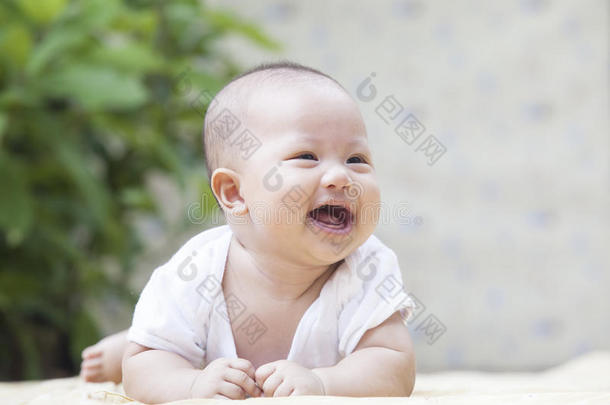 在家露台上躺在软床上微笑的婴儿的特写脸