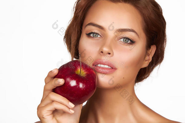 年轻漂亮的女孩，深色卷发，光着肩膀和脖子，抱着大苹果品尝美味，正在节食，