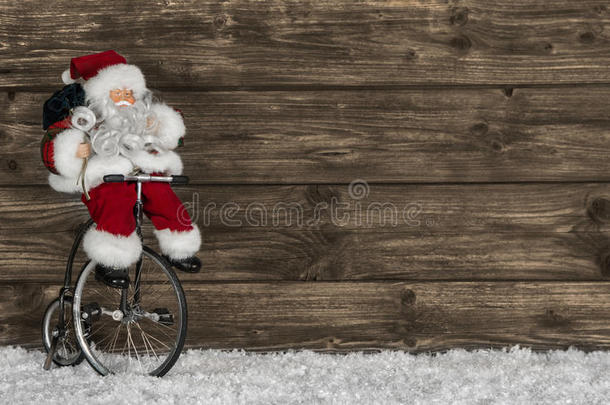 圣诞木背景，圣诞老人骑自行车。有趣的问候语