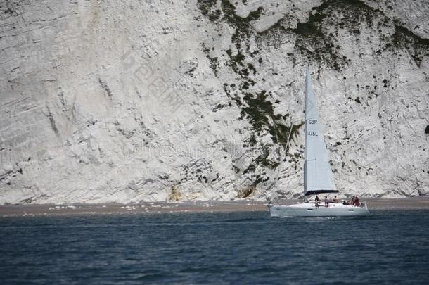 一艘帆船在靠近海岸的白色悬崖下沿着大海行驶