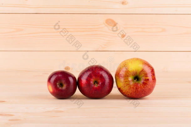 木头背景上有三个<strong>新鲜</strong>的<strong>红苹果</strong>。