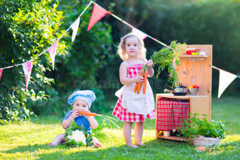 小孩子在花园里玩玩具厨房图片